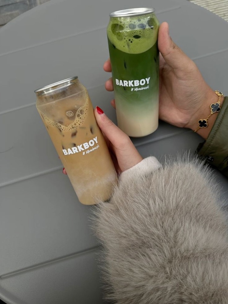 Two friends holding branded cans of iced coffee and matcha