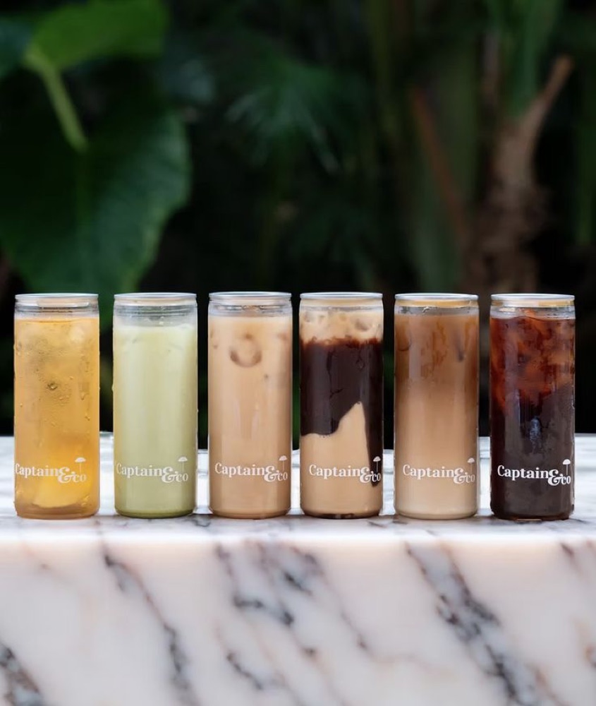 A lineup of six clear cans with a cafe's own branding
