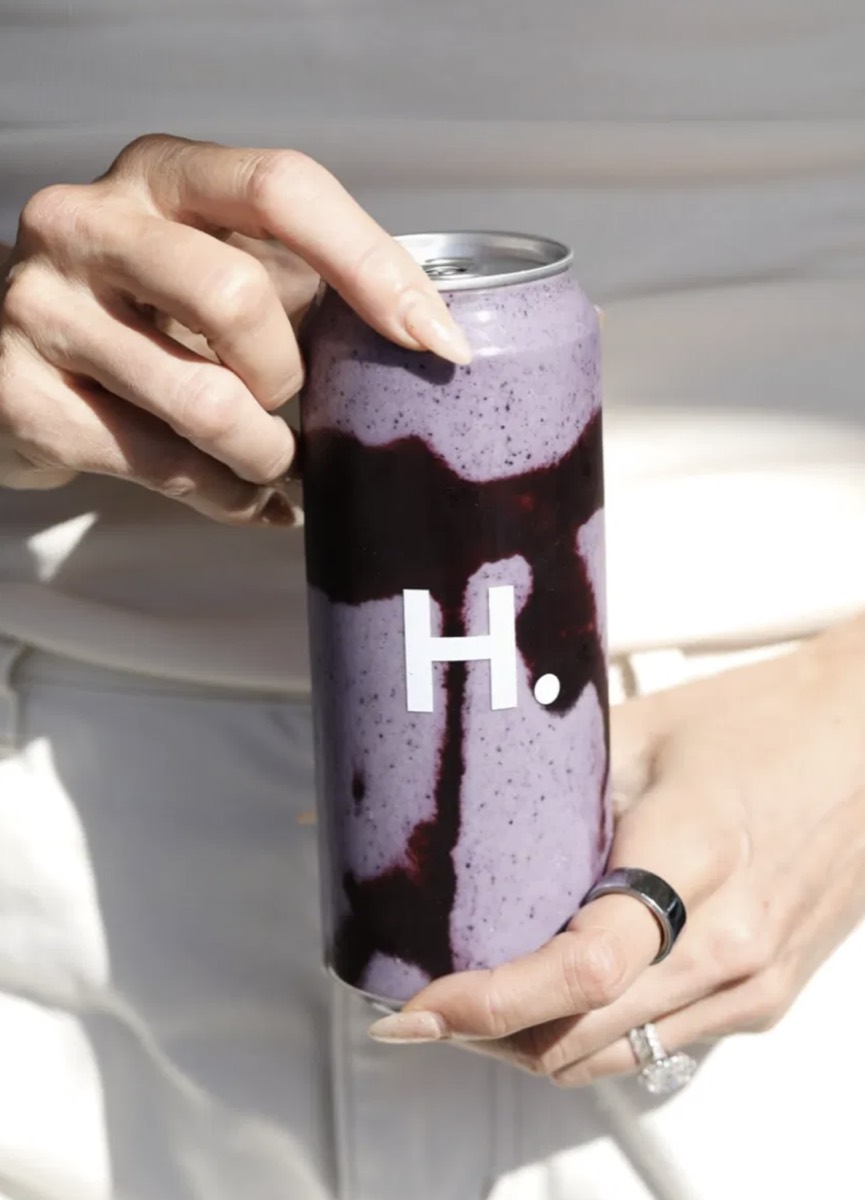 A can printed with a shop's own logo, held in two hands