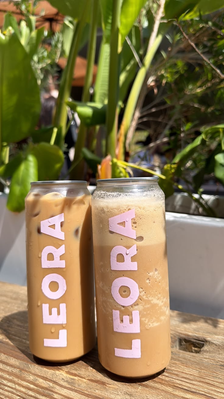 Two iced coffee cans with a name printed in big pink letters