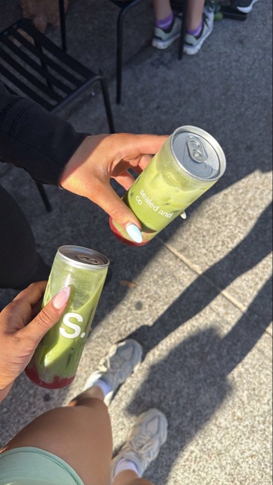Two friends outside a gym holding sealed and co matcha cans