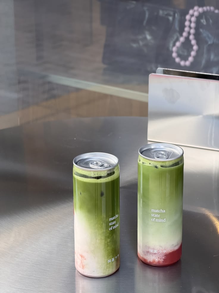 Two branded matcha cans on a steel table